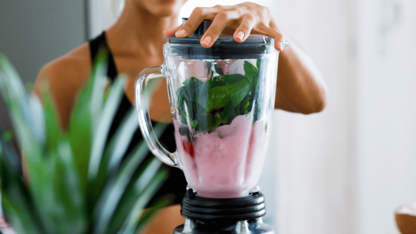 Woman blending berry matcha smoothie.