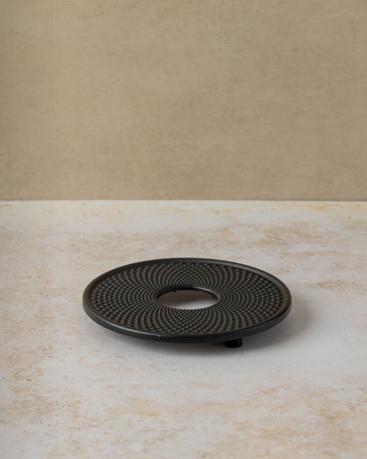 Black cast iron trivet with hobnail design, by The Tea House