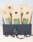 Five packs of green tea in a black gift box with a black and gold ribbon