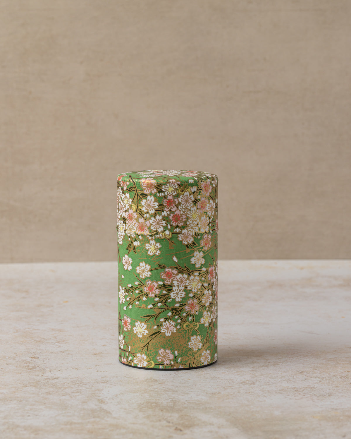 Cylindrical tea caddy with pink and white cherry blossom design on green background 
